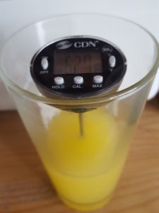 Food thermometer in orange juice checking that it is cold.
