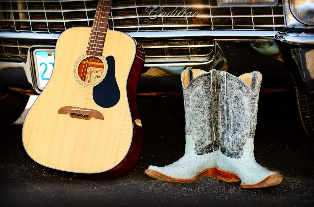 A guitar and a pair of cowboy boots representing country music.