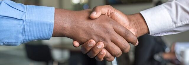 Two people shaking hands as though formalizing a relationship between a food safety consultant and business owner.